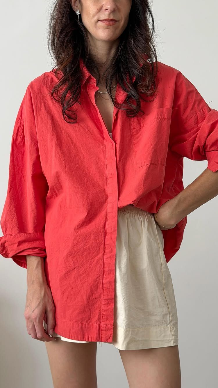 Shirt Tuck In Ideas: 4 Styles from Full Tuck to Knot 2 Person wearing a red button-down shirt with one side tucked into white shorts.