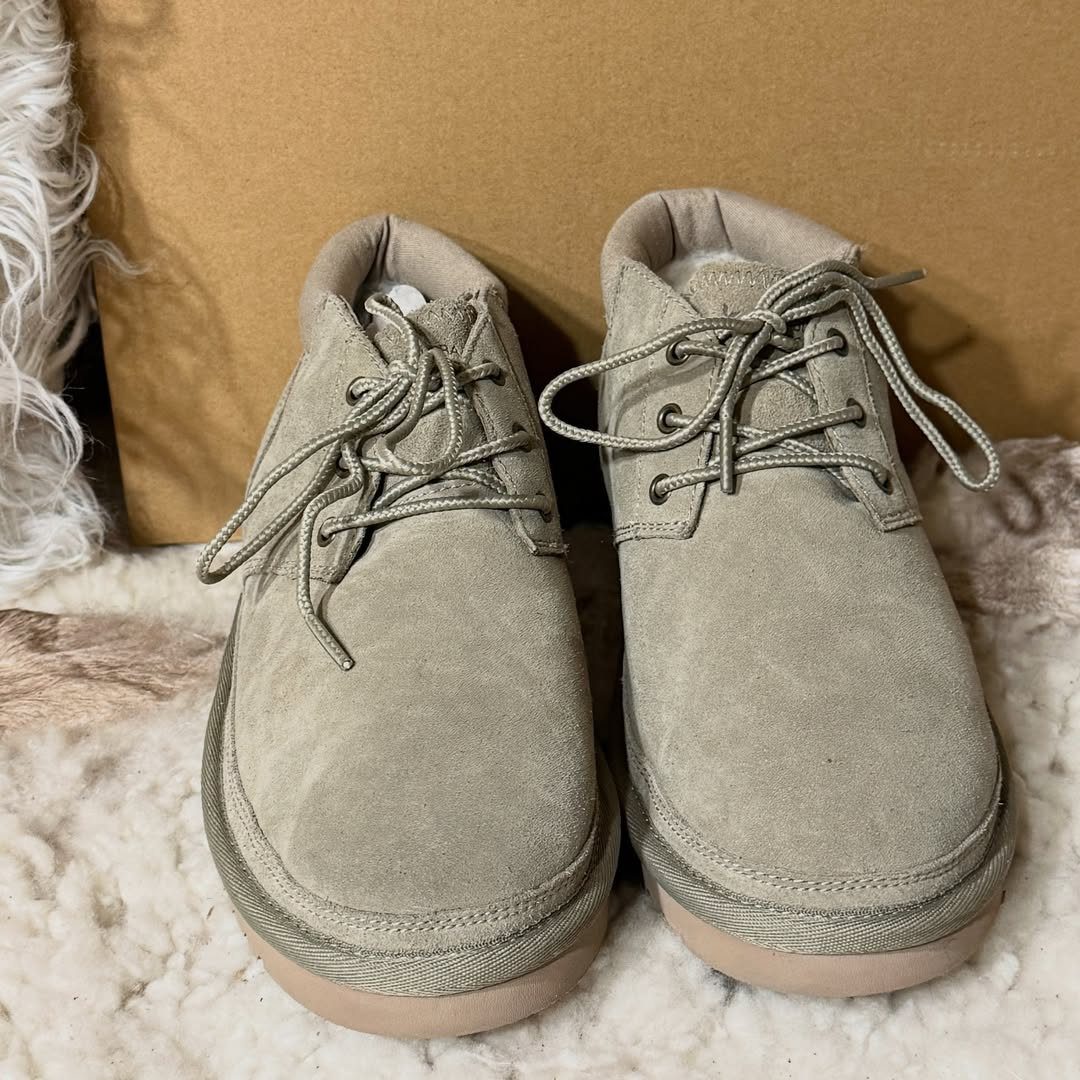 Beige suede lace-up ankle boots with fur lining on a white fluffy rug.