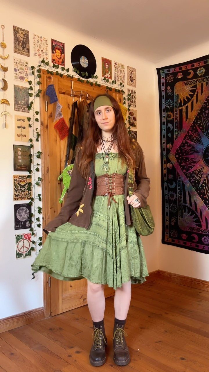 Woman wearing a green hippie dress with a brown corset and headband.