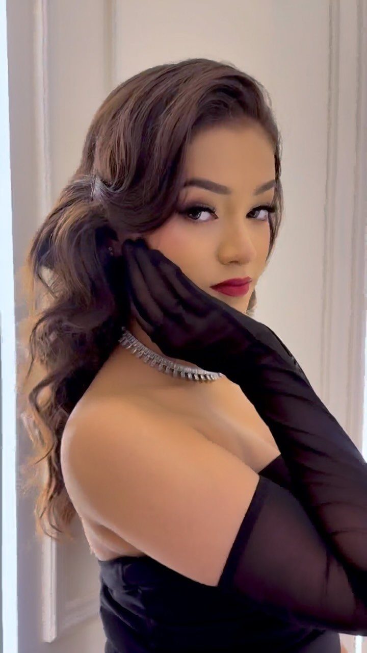 Woman in a black strapless dress and sheer gloves with vintage Hollywood styling.