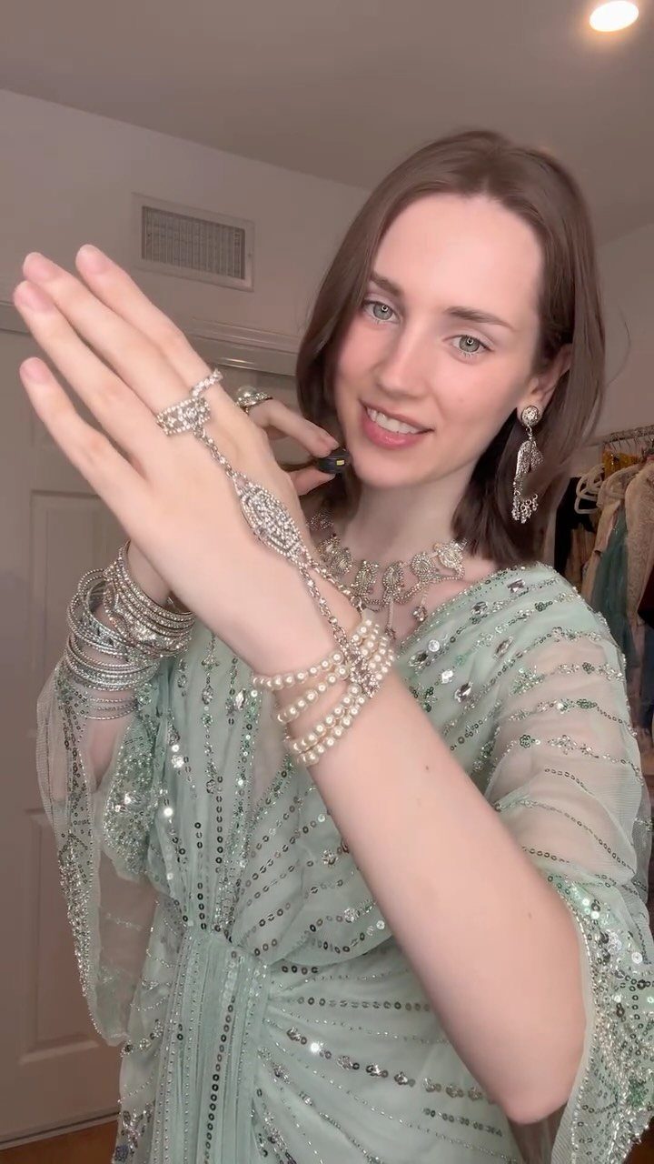 Woman in a light green sequined flapper dress wearing pearls and sparkling jewelry.