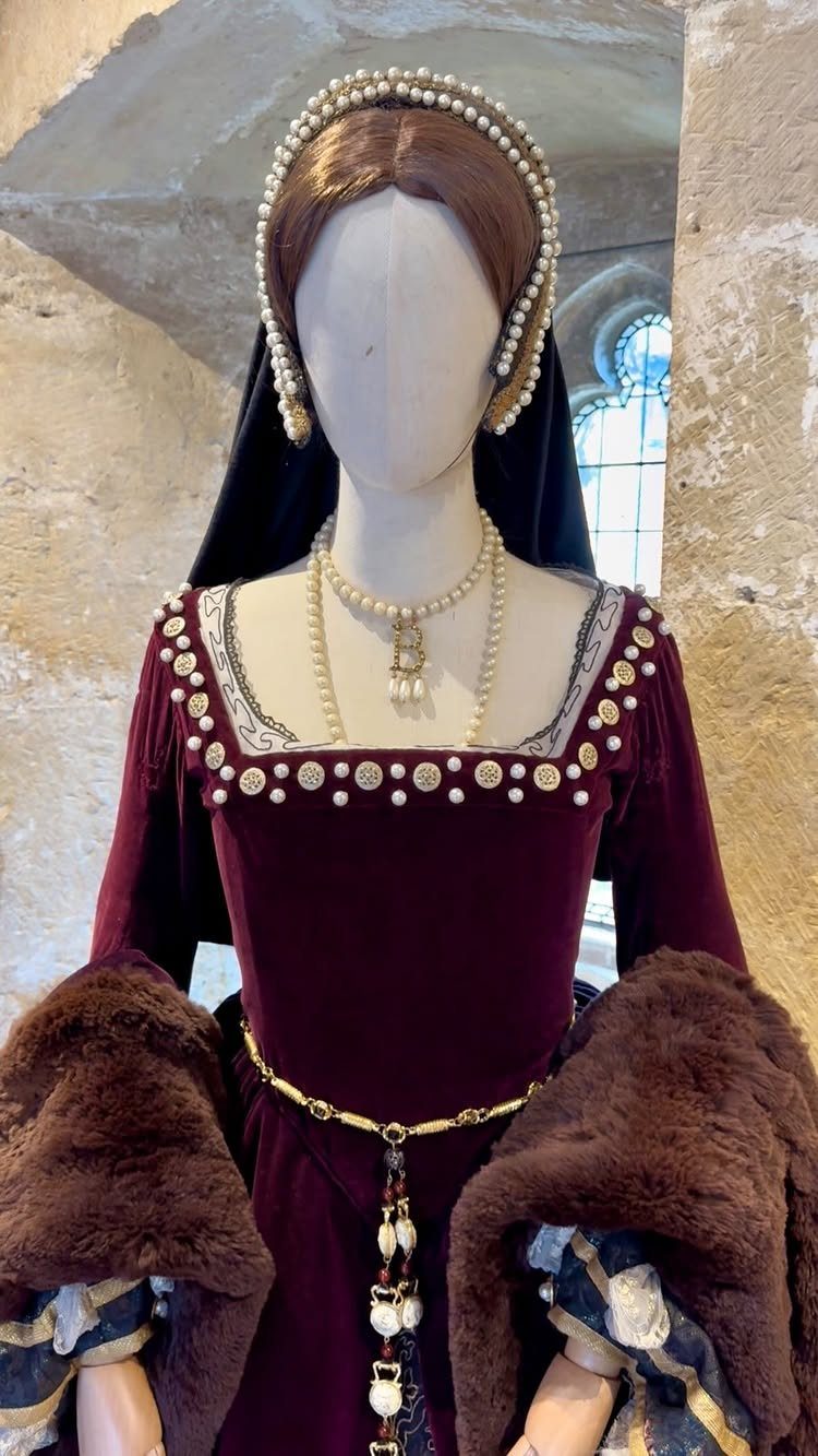 Burgundy velvet Tudor gown with pearl details and fur trim on a mannequin.