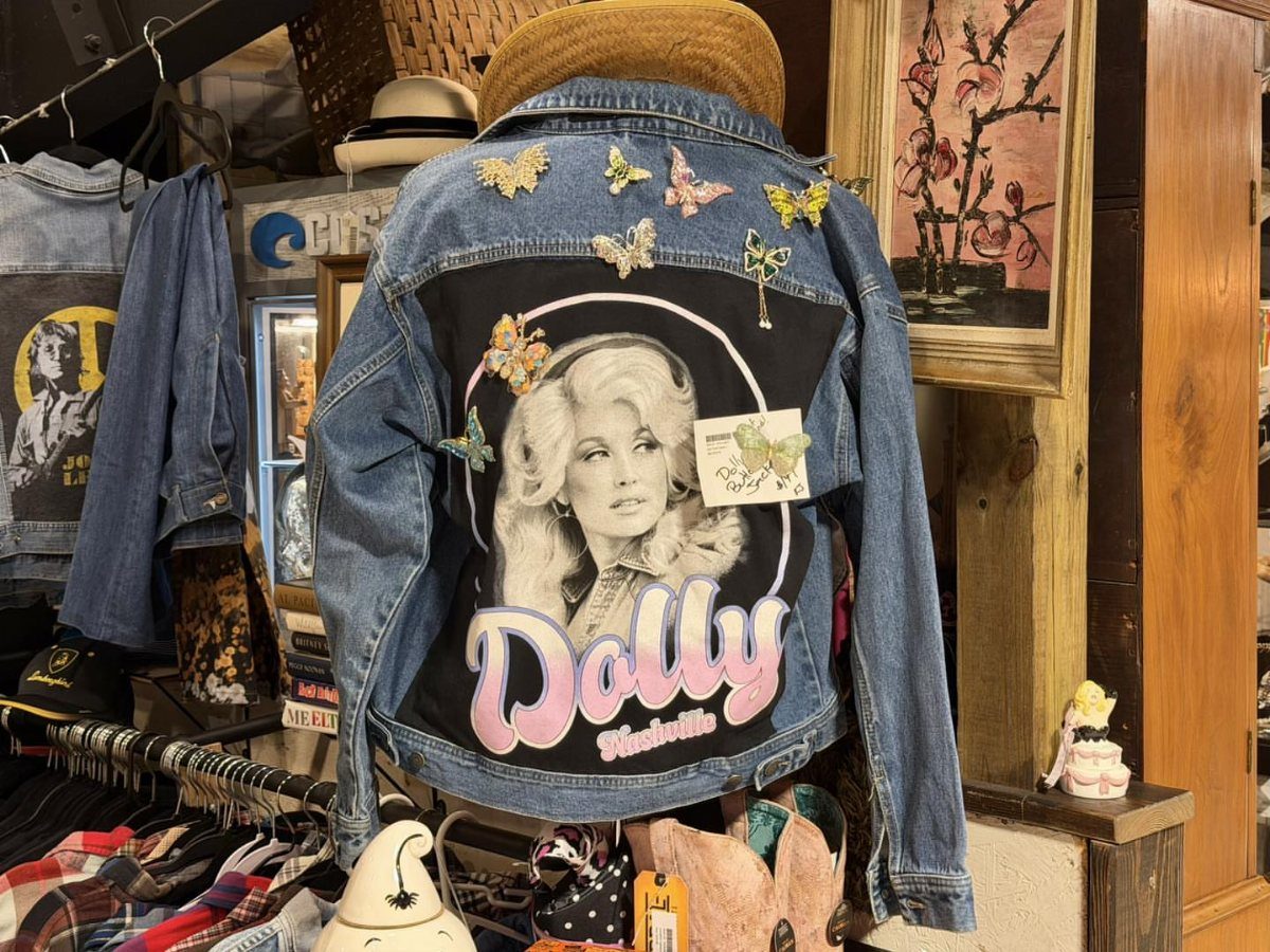 Blue denim jacket with a Dolly Parton graphic and butterfly accents on display.