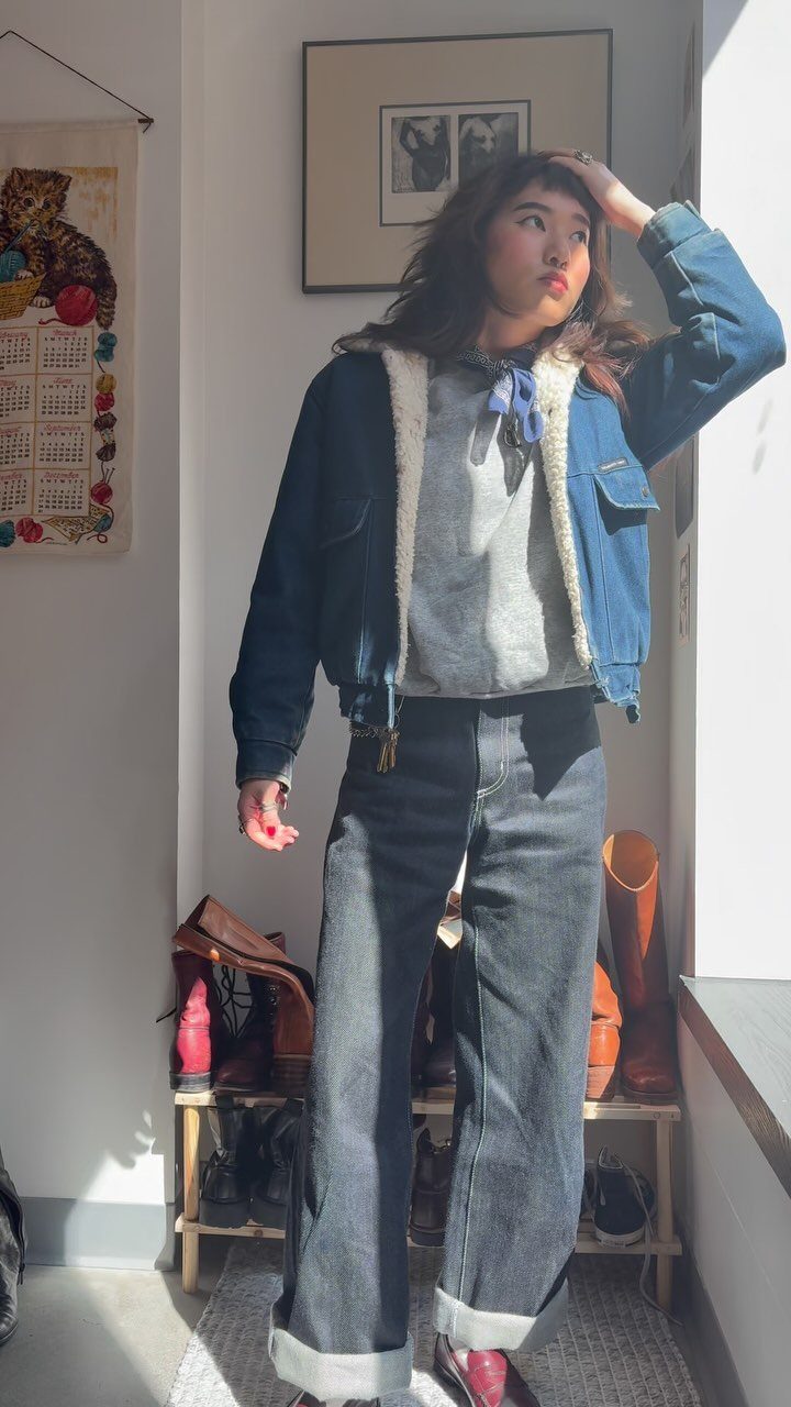Woman wearing a denim jacket and dark blue wide-leg jeans with cuffed hems.