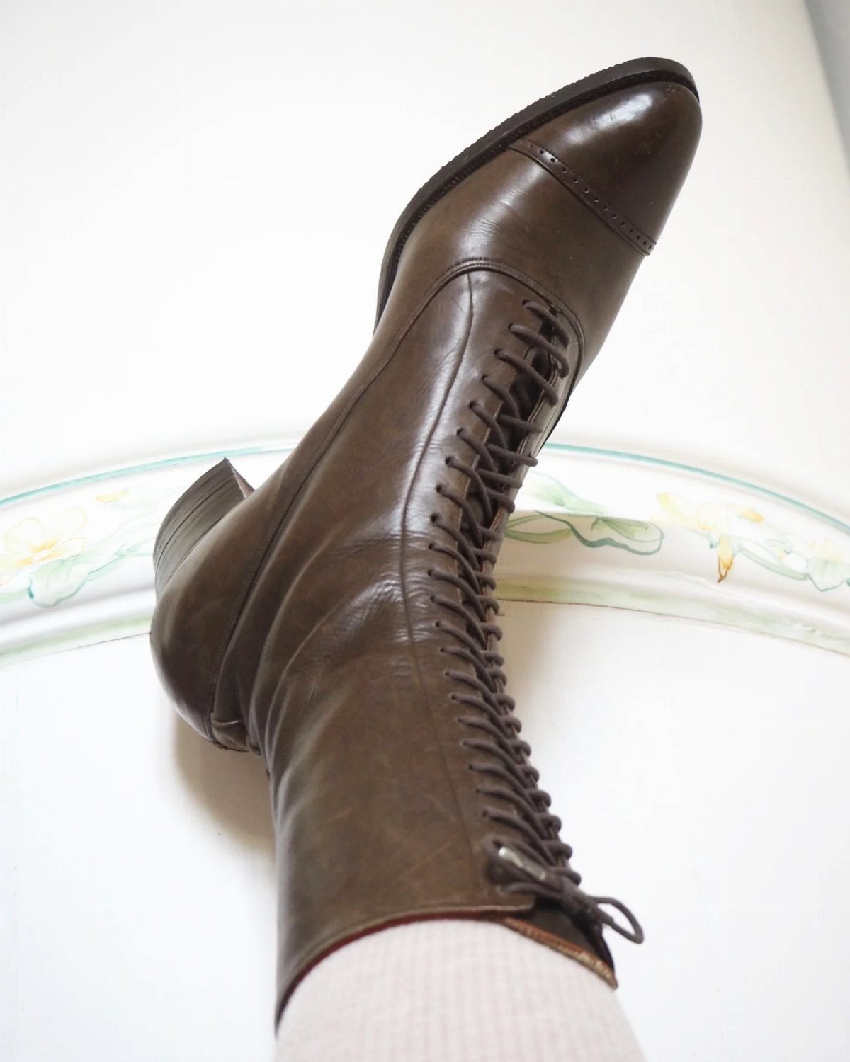 Vintage Shoes and Heels: 8 Styles From Mary Janes to Boots 7 Brown leather lace-up boot with low heel worn with a white sock.