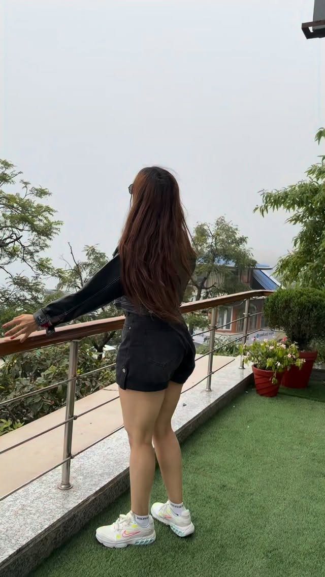 Woman from behind wearing a black leather jacket and black denim shorts.