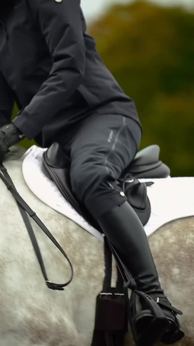 Person in black riding gear and tall boots sitting on a white horse