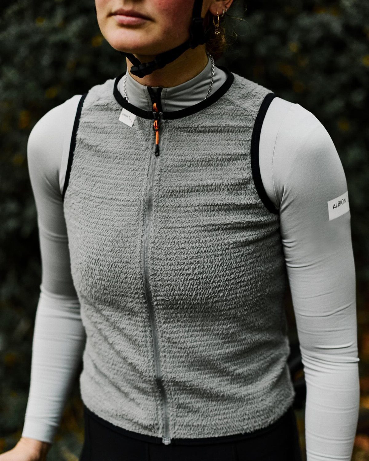 Person wearing a grey fleece vest and long-sleeved shirt for outdoor riding.