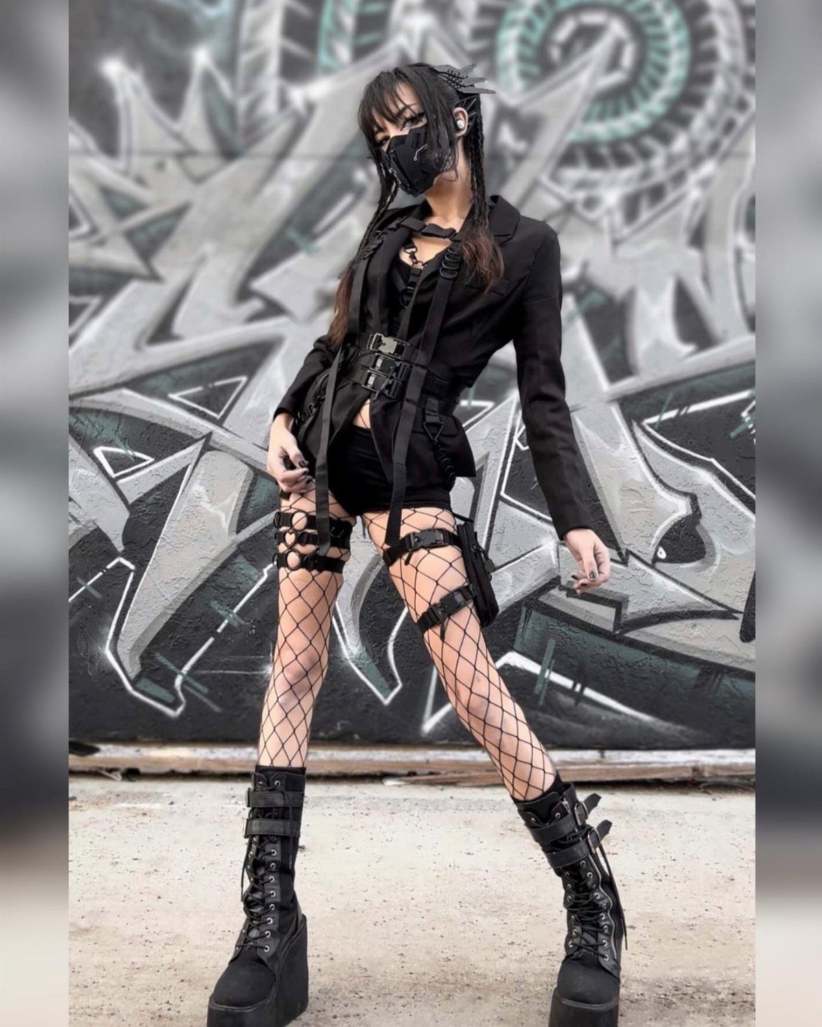 10 Woman Rave Outfit Ideas for Festival Nights 4 Woman in all-black techwear outfit with platform boots posing against graffiti wall
