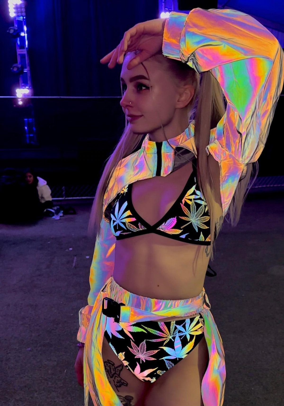 10 Woman Rave Outfit Ideas for Festival Nights 9 Woman in iridescent cropped jacket and leaf-print bikini posing at a night event