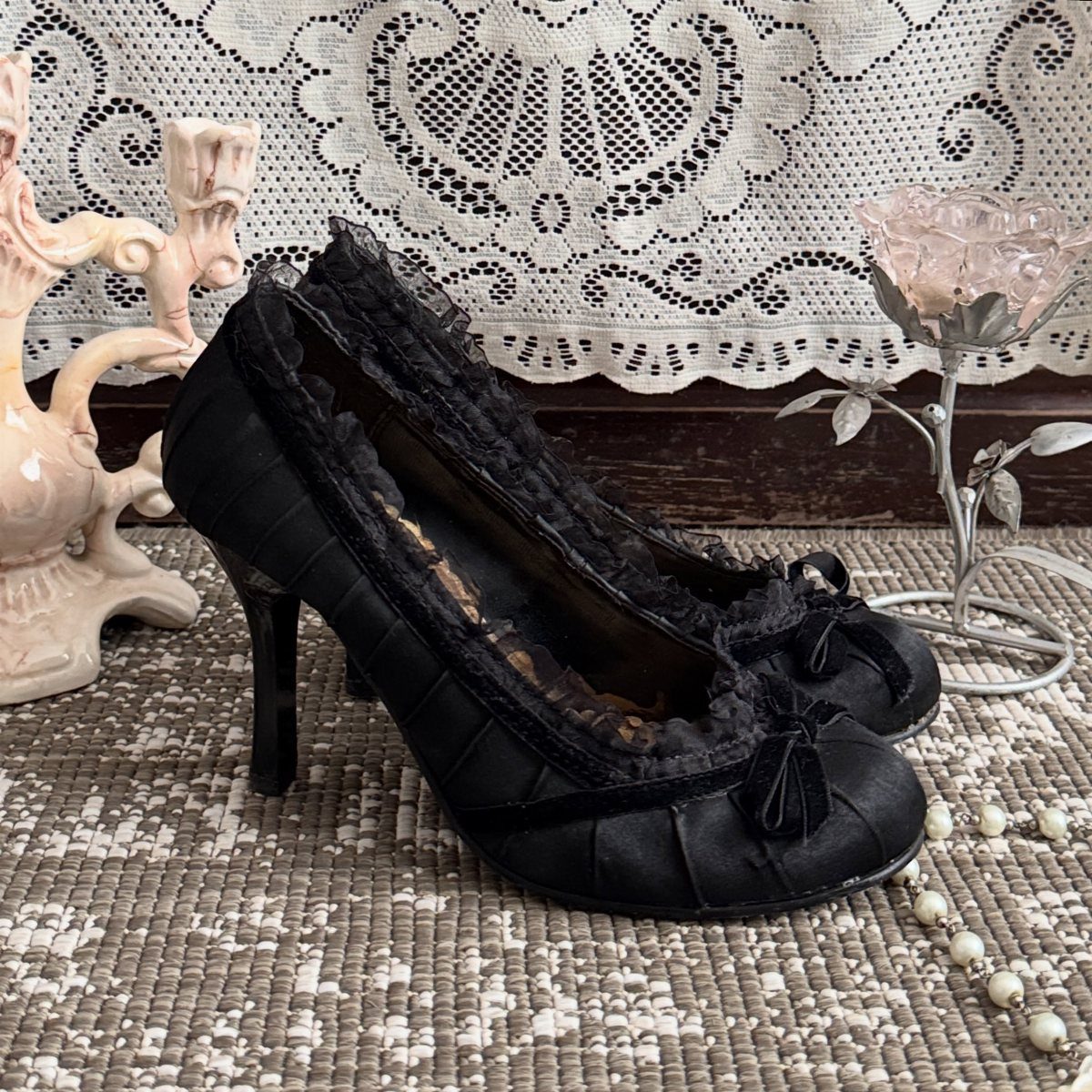 Black lace-trimmed pumps with bows on the toes and medium heels.