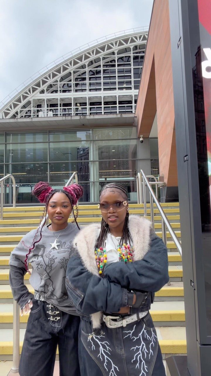 Two women posing outdoors, one wearing a black jacket with white faux fur collar.