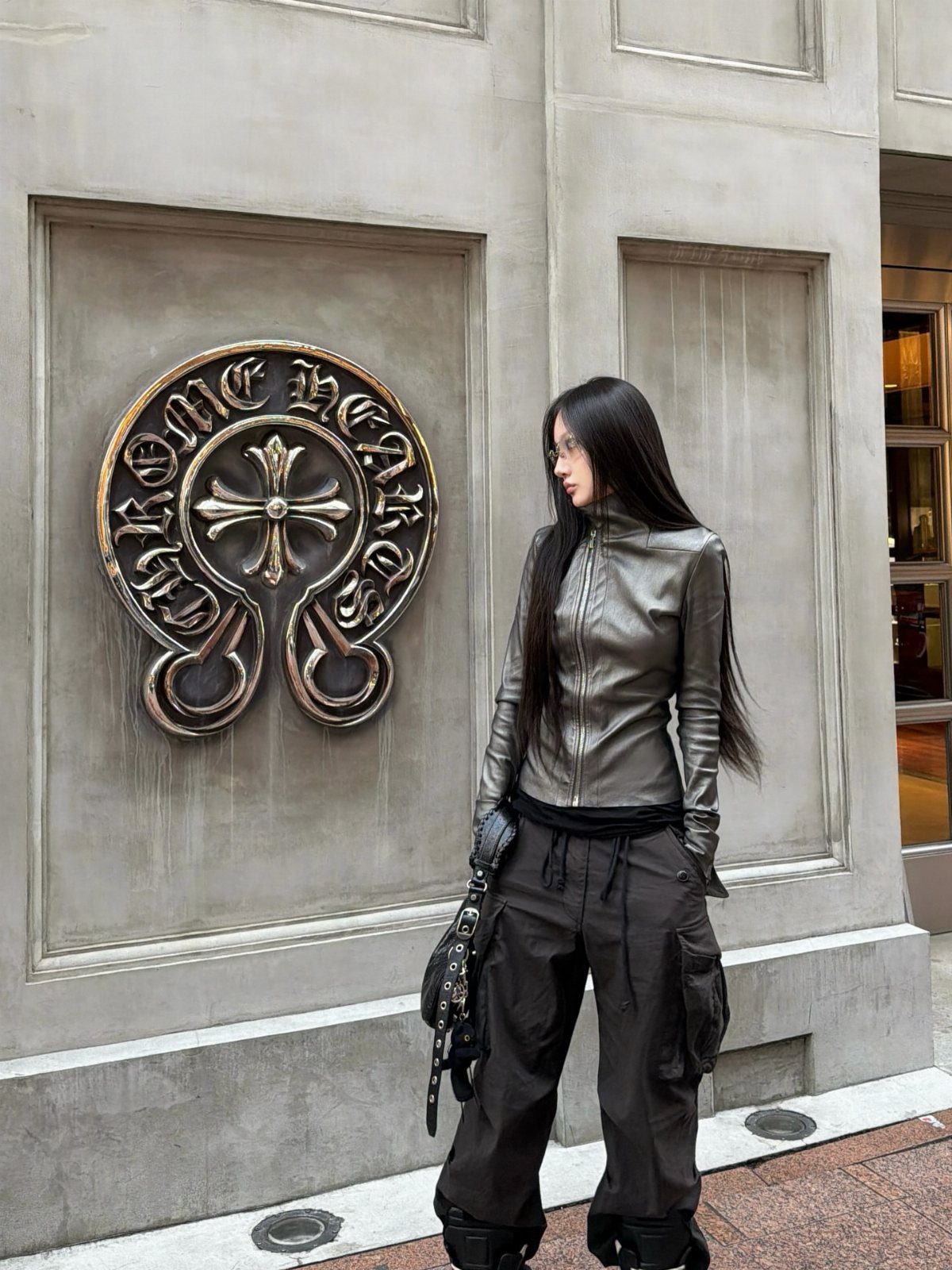 Woman wearing metallic silver top and black cargo pants by a stone wall.