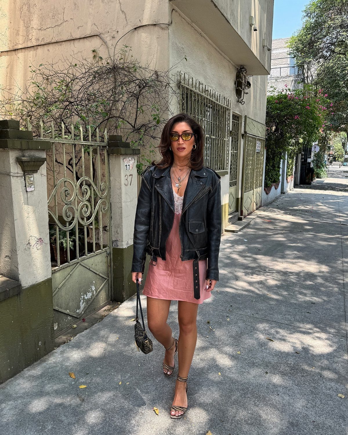 Woman wearing a pink satin slip dress and black leather jacket on a sidewalk