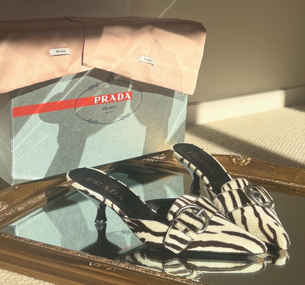 Zebra Kitten Heels: 7 Styles from Slingbacks to Mules 6 Zebra print kitten heel mules with silver buckles on a mirrored tray.