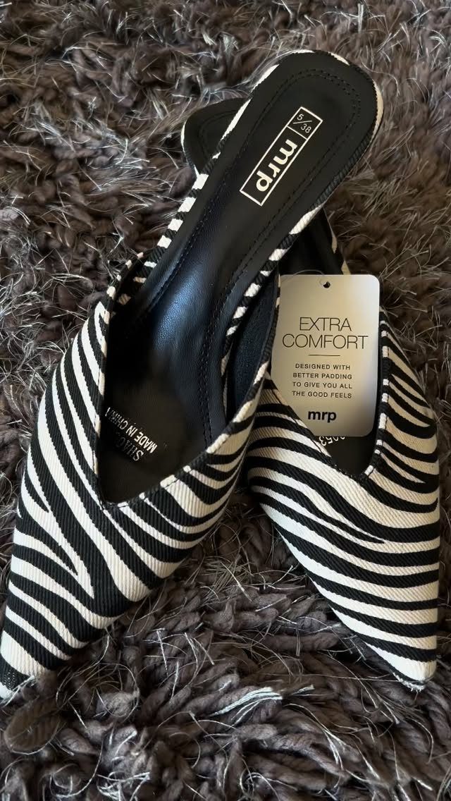 Zebra Kitten Heels: 7 Styles from Slingbacks to Mules 7 Zebra print kitten heel mules resting on a grey shaggy faux-fur rug.